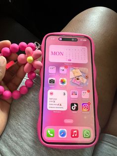 a person holding a pink cell phone with beads attached to it