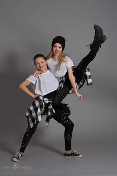 two people are posing for the camera in black and white outfits, one is holding on to the other's leg