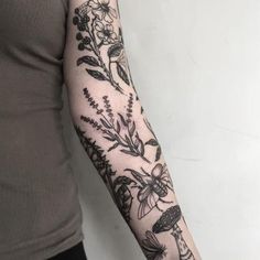 a woman's arm with flowers and bees on it, while she is wearing a grey shirt