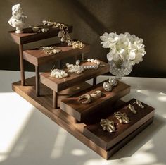 three tiered wooden display with flowers and jewelry