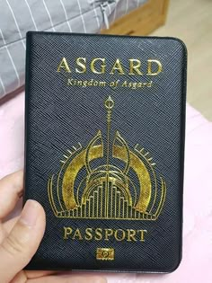 a person holding up a black passport in their hand with the word asgard written on it