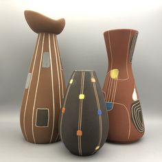 three vases sitting side by side on a white surface, each with different designs