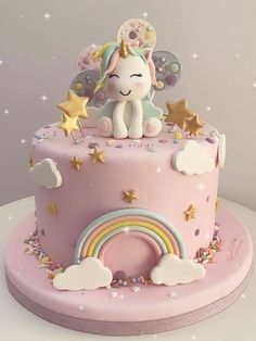 a pink cake with a unicorn sitting on top of it and stars around the edges