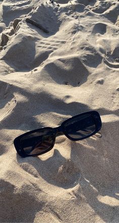 a pair of sunglasses laying in the sand