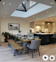 a dining room table with two chairs and a bench in front of an open kitchen