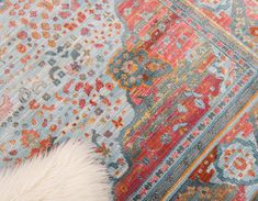 a white furry animal laying on top of a colorful rug