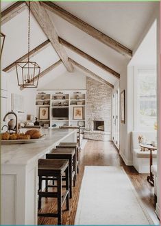 an open kitchen and dining room with exposed beams in the ceiling, along with white counter tops