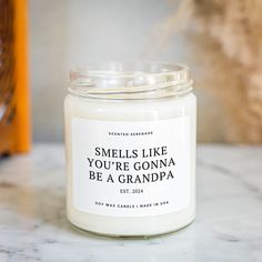 a white candle sitting on top of a marble counter next to a bottle of soap