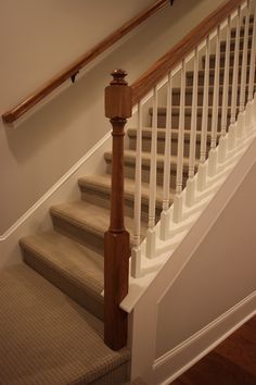 the stairs are made of wood and have white balustiers on them, along with carpet