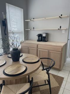 a dining room table and chairs in front of a wall mounted shelf with shelves on it