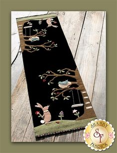 a black table runner with an animal and tree design on the front, along with a brown border