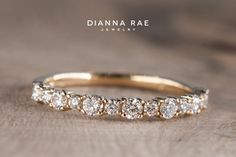 a gold wedding band with five diamonds on it, sitting on a wooden surface in front of the words dana rae jewelry