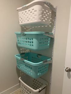 three baskets stacked on top of each other next to a door in a room with white walls