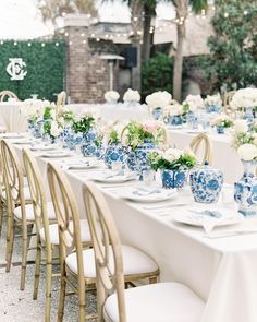 a long table with blue and white china on it is set for a formal dinner