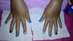 a woman's hands with blue and white nail polish on her nails, sitting on a towel