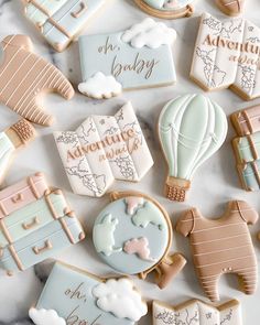 decorated cookies are arranged on a marble countertop with the words adventure await and hot air balloons