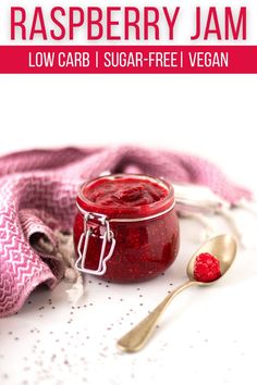 raspberry jam in a glass jar with spoons and pink towel on the side