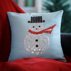 a white pillow with a snowman made out of buttons and sequins on it