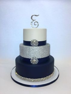 a three tiered blue and white wedding cake with silver glitter decorations on the top