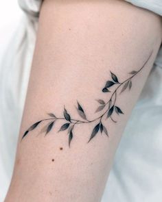 a woman's arm with a tattoo on it that has leaves growing out of it