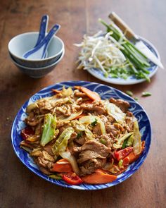 a blue plate topped with meat and veggies on top of a wooden table