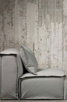 a gray couch sitting in front of a wooden wall