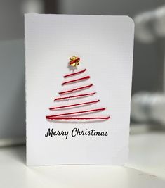 a white card with a red christmas tree on it