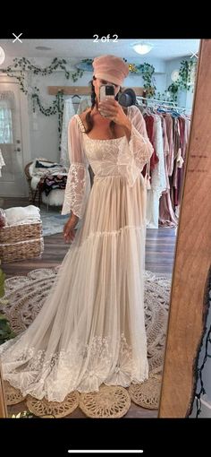 a woman taking a selfie in front of a mirror wearing a white dress and hat