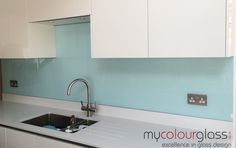 a kitchen with white cabinets and blue glass backsplash