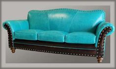 a blue leather couch sitting on top of a white floor next to a wooden frame