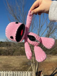 a hand holding a pink crocheted stuffed animal