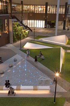 an aerial view of people sitting on benches in the middle of a courtyard at night