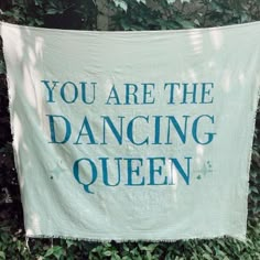 there is a banner that says you are the dancing queen hanging on a wall in front of some bushes