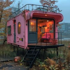 a pink house sitting on top of a lush green hillside next to a lake with stairs leading up to it