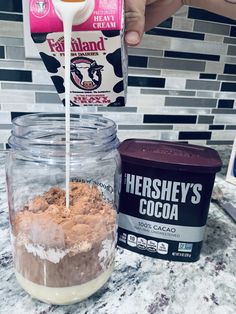 someone pouring cocoa into a glass jar on top of a counter next to a box of ice cream