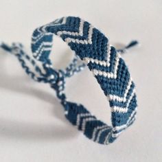 two blue and white woven bracelets sitting on top of each other with one knot in the middle