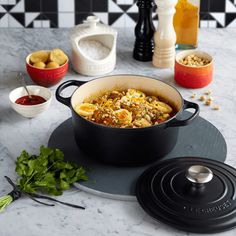 a pot filled with food sitting on top of a counter next to bowls and utensils