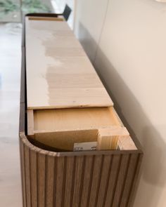 an empty drawer in the middle of a white counter top with wood trimming on it