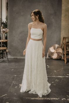 a woman wearing a white dress standing in an empty room