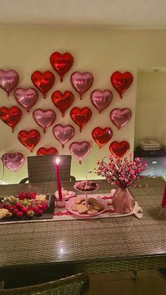 valentine's day table setting with heart shaped balloons on the wall and flowers in vases