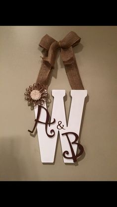 a wooden sign with the letter w on it and a bow hanging from it's side