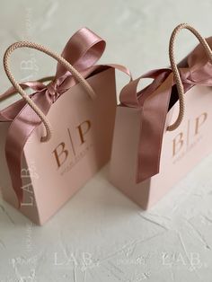 two pink gift bags tied with twine and labeled b p p f e s