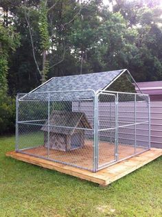 a small dog house in the middle of a yard with a chicken coop on top