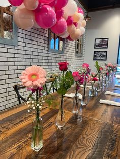 a long table with vases filled with flowers and balloons