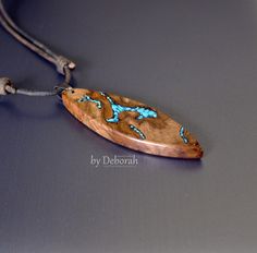 a wooden necklace with blue beads on a gray surface and a cord attached to it