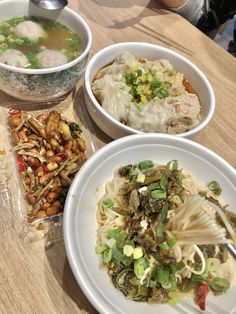 three bowls of food on a table with chopsticks and spoons next to them