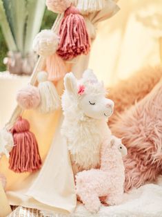 two stuffed animals sitting next to each other on a bed with pom poms