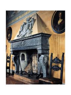 an old fireplace in the middle of a room with paintings on the wall behind it