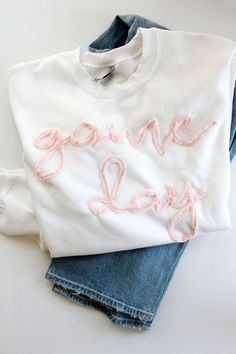 a white sweatshirt with the words game day written on it next to some blue jeans