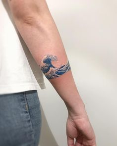 a person with a tattoo on their arm that has a wave in the middle of it